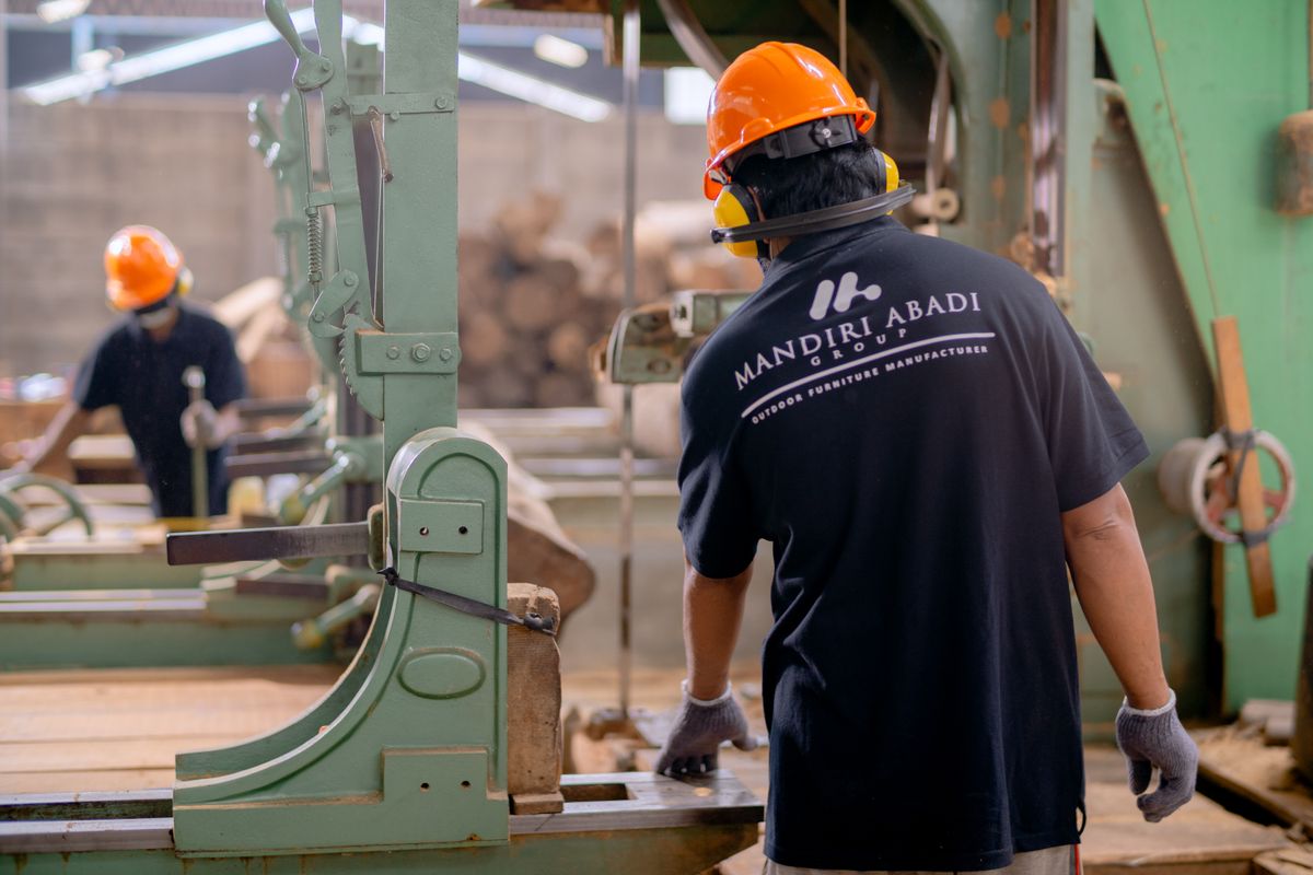 Công nhân mặc đồ bảo hộ vận hành thiết bị trong nhà xưởng.