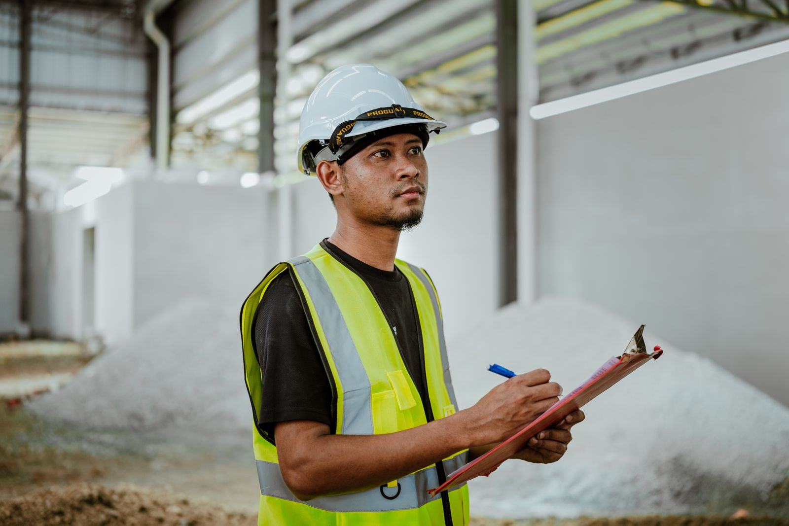 Nhân viên cầm bảng kẹp giấy để kiểm tra công việc trong nhà xưởng.