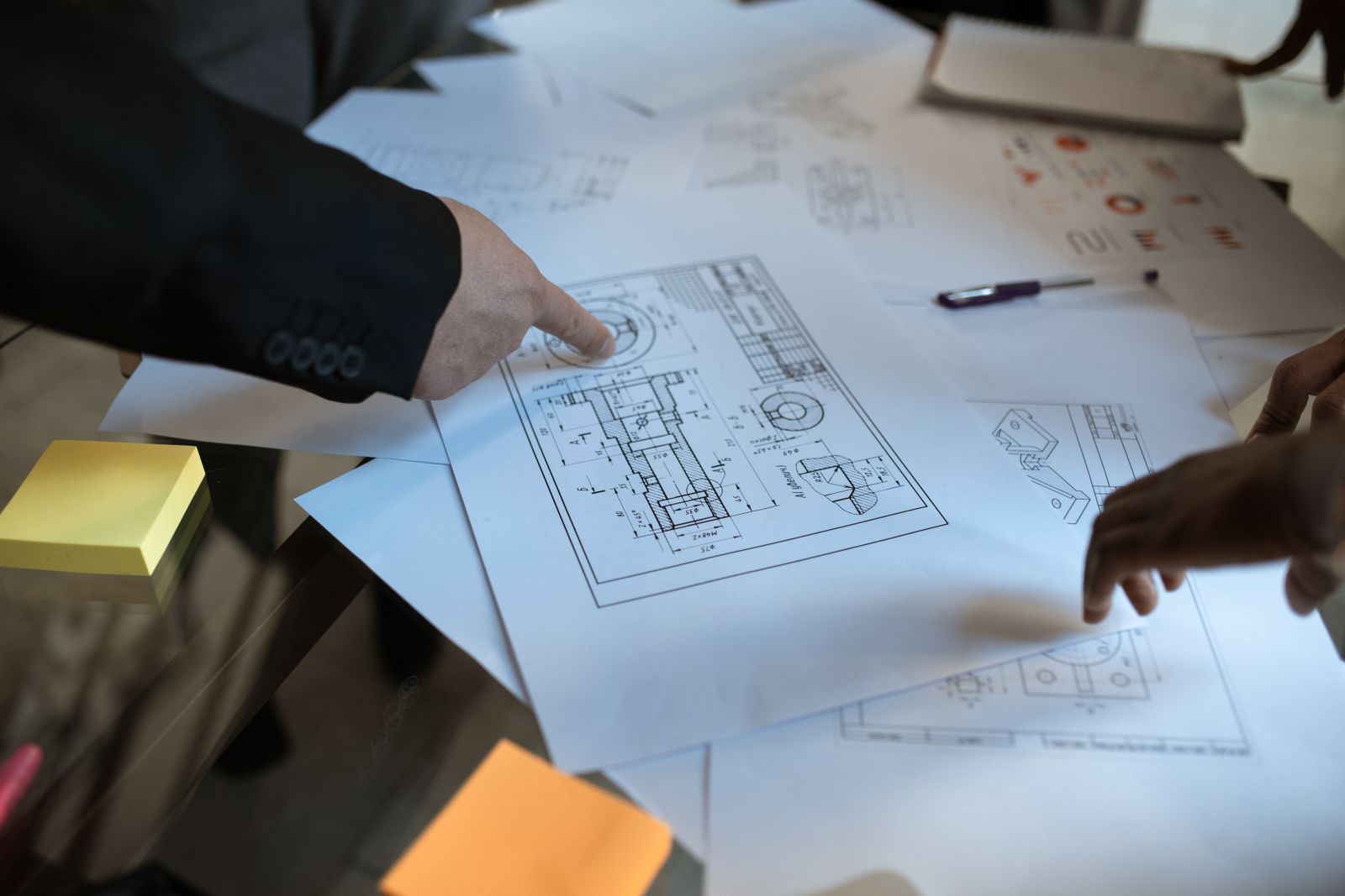 Bàn tay chỉ vào một chi tiết trên bản vẽ trong buổi thảo luận dự án.
