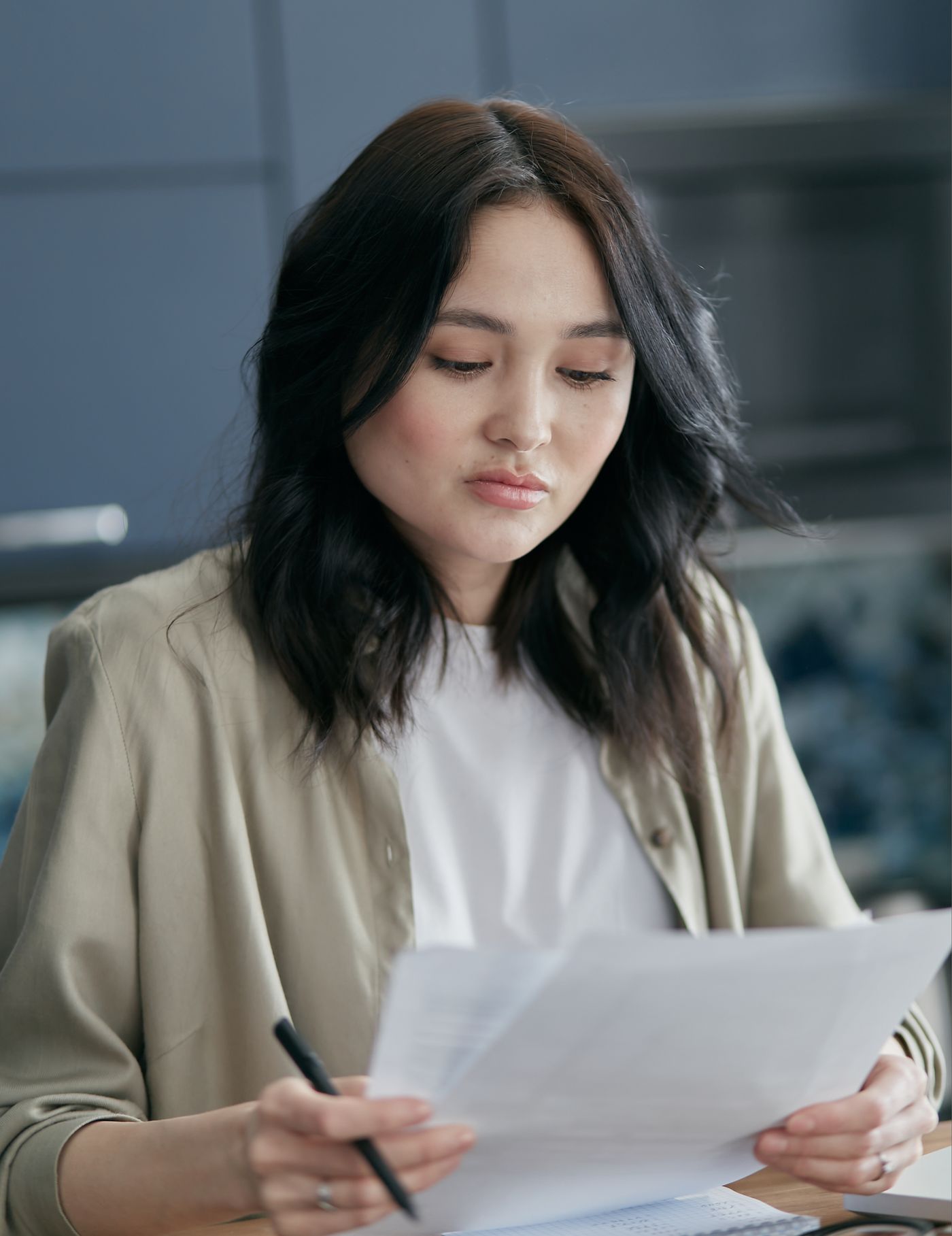 Người phụ nữ cầm bút đọc và rà soát tài liệu.