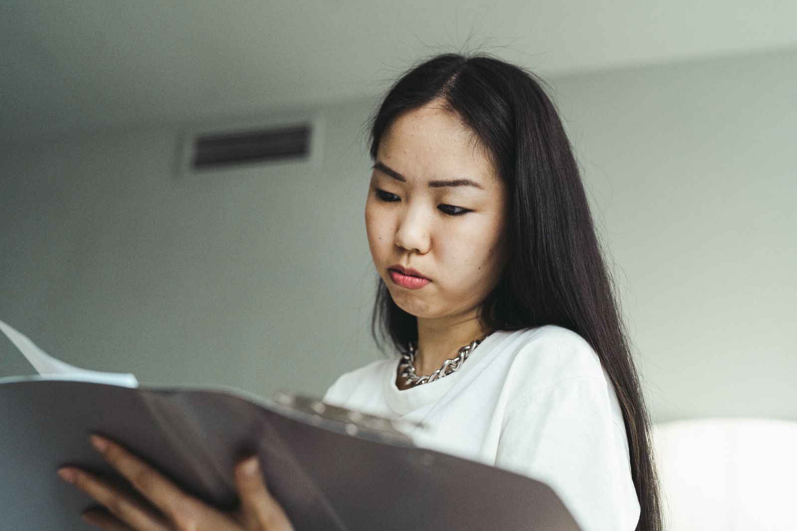 Một phụ nữ tập trung xem các trang tài liệu trong phòng làm việc.